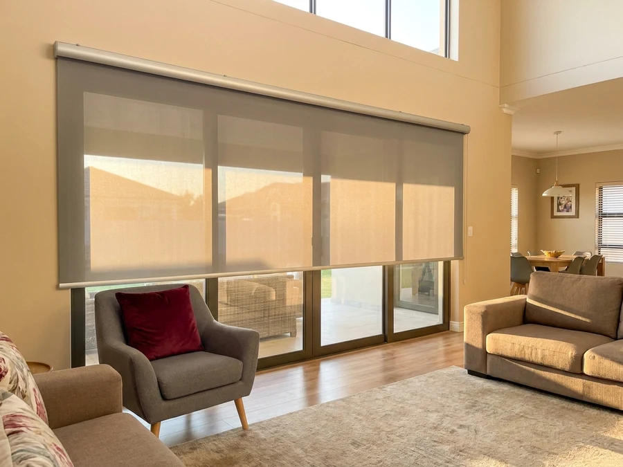 Sunscreen roller blind extended over a stacker door in a Brackenfell family lounge